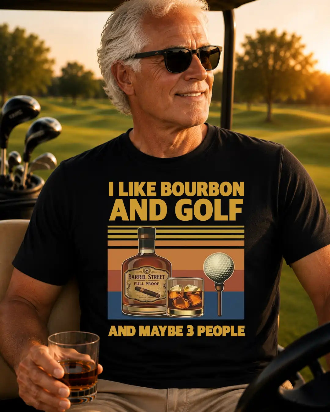 A smiling older man wearing sunglasses sits in a golf cart on a golf course at sunset, holding a glass of whiskey. He wears a black graphic T-shirt with yellow text reading 'I LIKE BOURBON AND GOLF AND MAYBE 3 PEOPLE' and a retro-style print of a bourbon bottle, a drink, and a golf ball.