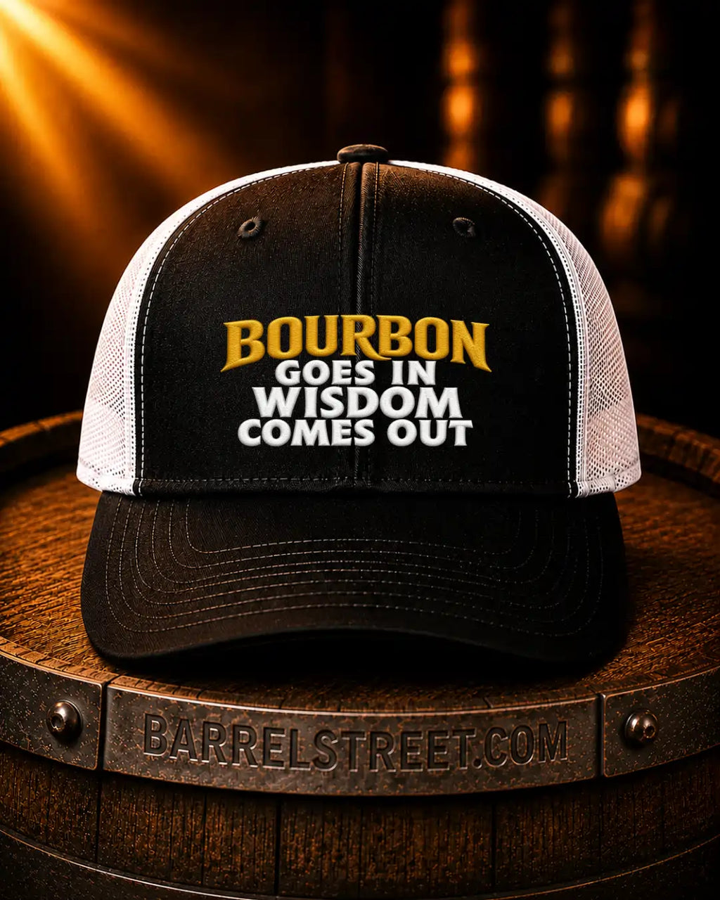 A black and white trucker cap with the text 'BOURBON GOES IN WISDOM COMES OUT' in yellow and white on the front, displayed on a wooden barrel with a Barrelstreet.com logo.