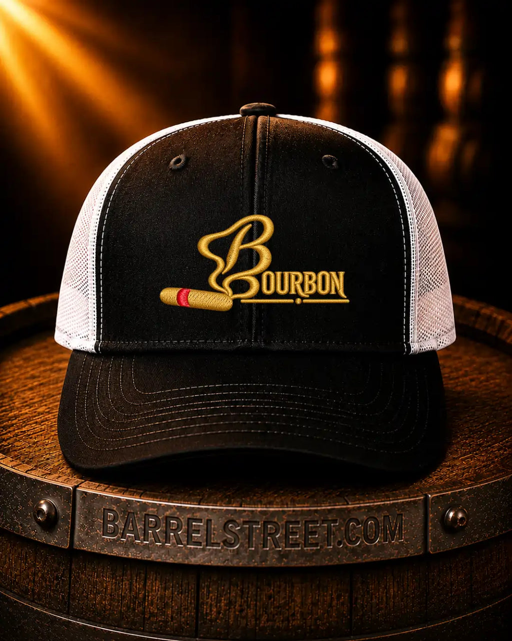 Black and white trucker cap with a gold embroidered Bourbon logo and a gold-and-red bullet graphic on the front, displayed on a wooden barrel with warm spotlighting.