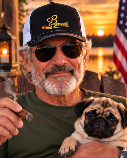 A man wearing a black and white trucker hat with a 'Bourbon' logo and sunglasses, holding a cigar and a pug dog, set against a warm sunset lake background with an American flag.