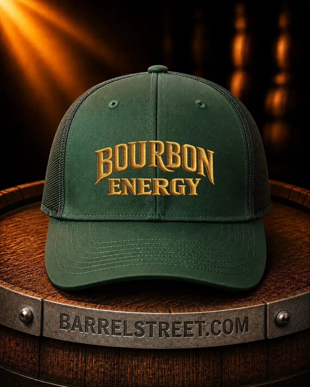 A dark green trucker-style baseball cap with gold embroidered text reading 'BOURBON ENERGY' on the front, displayed on a wooden barrel with a metal band engraved 'BARRELSTREET.COM'.