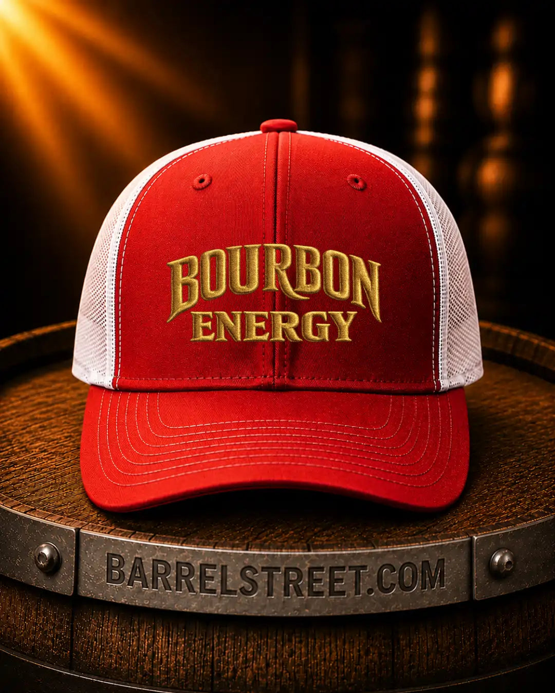 A red and white trucker hat with gold embroidered 'BOURBON ENERGY' text on the front, displayed on a wooden barrel with a Barrelstreet.com logo on the band.