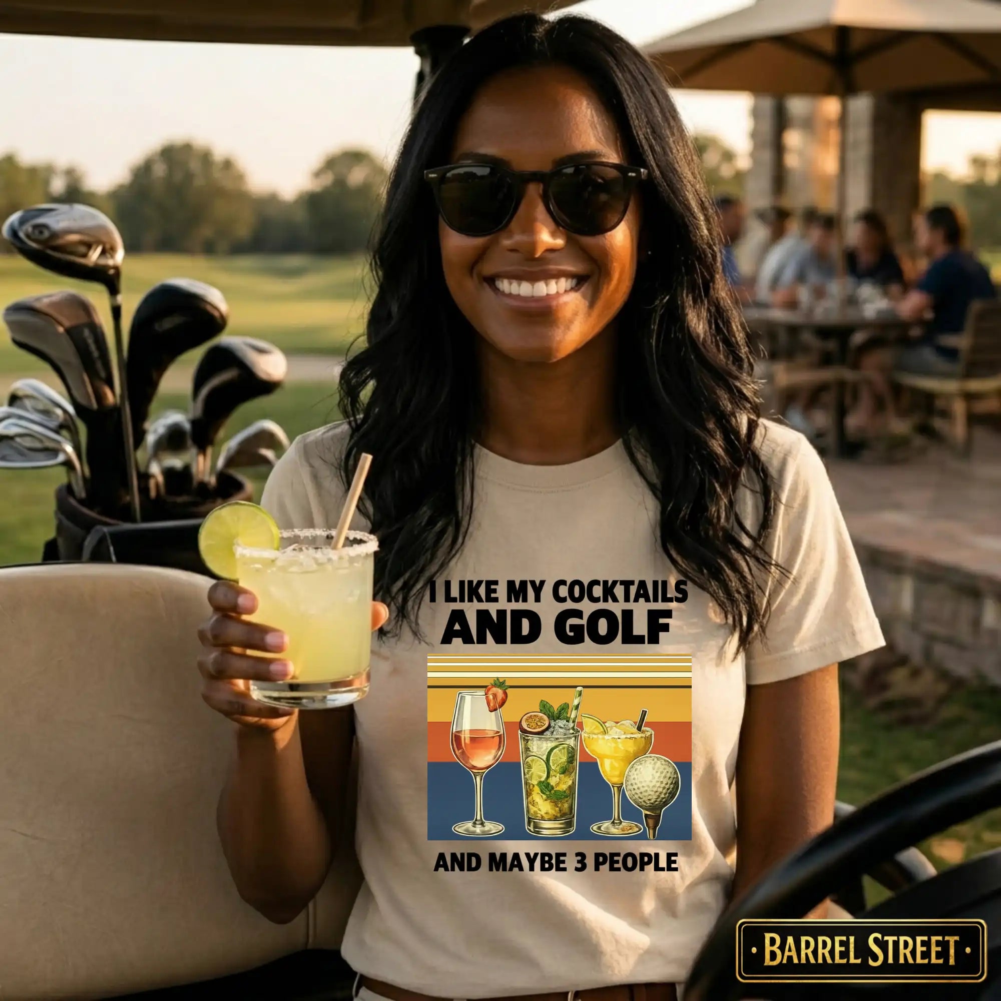 Woman holding a cocktail with golf clubs and people in the background, wearing a 'Barrel Street' t-shirt.