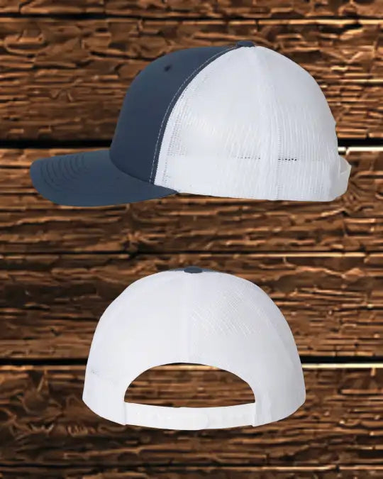 A two-tone trucker cap shown from the side and back views against a rustic brown wood plank background. The front panels and brim are navy blue, while the back mesh is white.