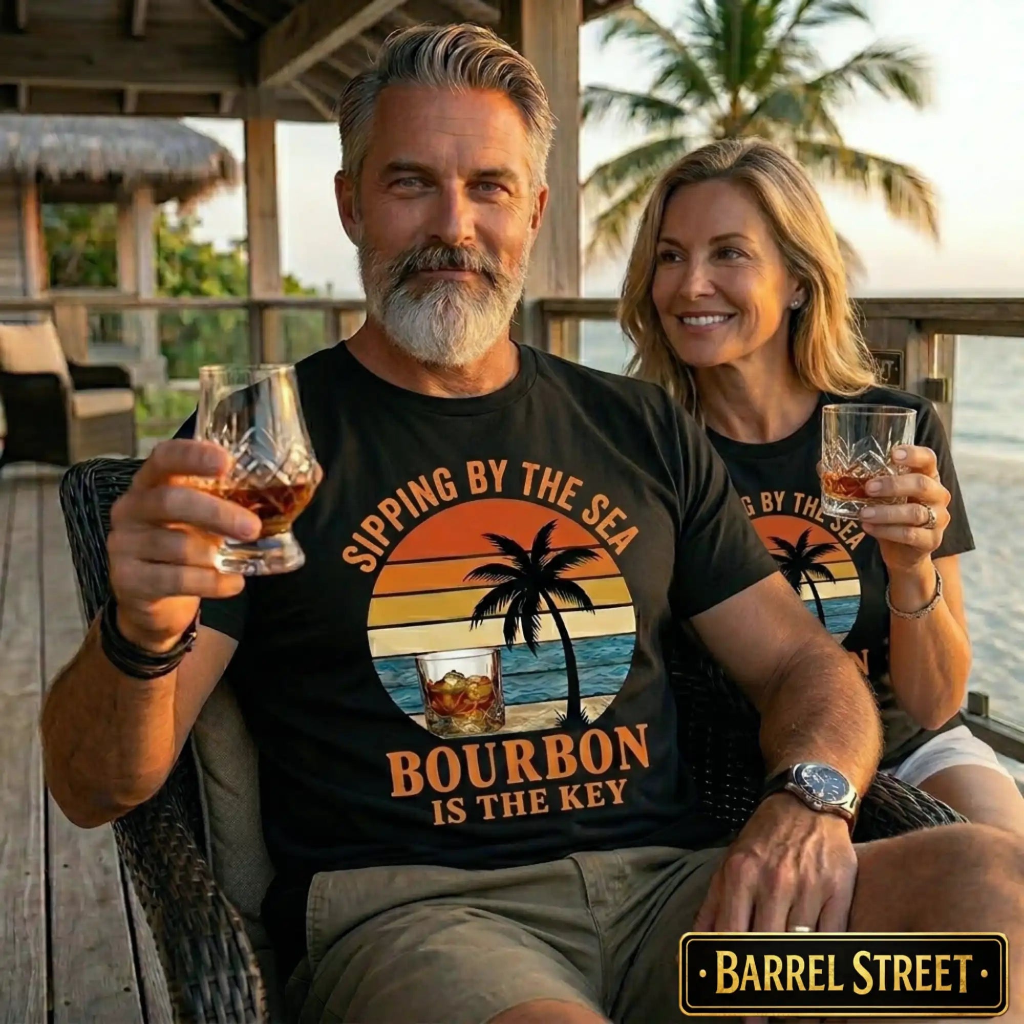 Man and woman sitting together, both holding glasses of bourbon, wearing matching t-shirts with a sunset design and text.