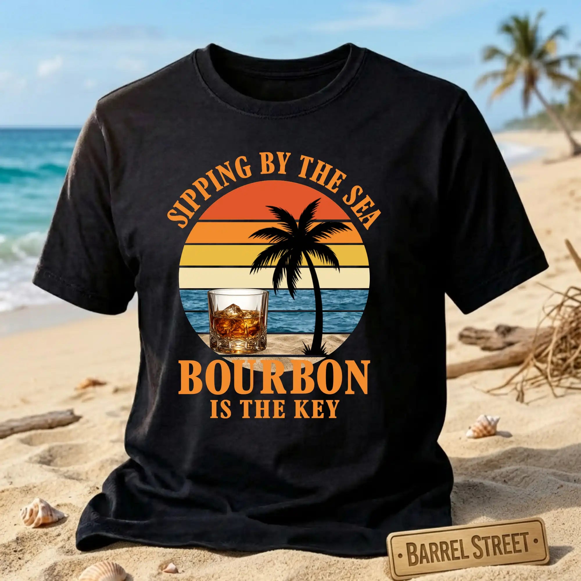 Black t-shirt with 'Sipping by the Sea, Bourbon is the Key' design on a beach background