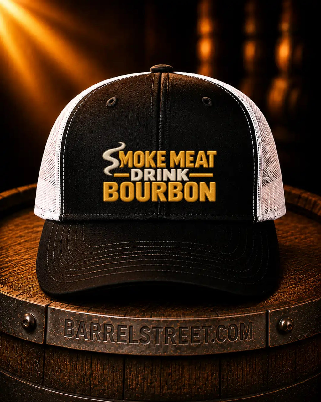 A black and white trucker hat with 'SMOKE MEAT DRINK BOURBON' embroidered on the front, resting on a wooden barrel with a Barrelstreet.com logo visible on the front band.
