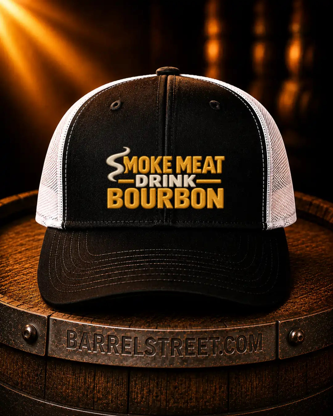 A black and white trucker hat with 'SMOKE MEAT DRINK BOURBON' embroidered on the front, resting on a wooden barrel with a Barrelstreet.com logo visible on the front band.