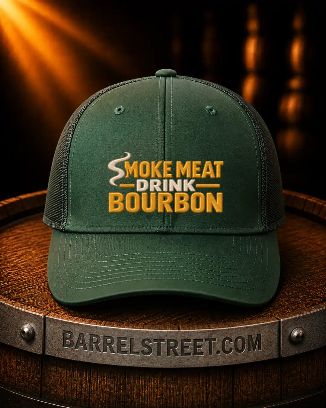 A dark green trucker-style cap with 'SMOKE MEAT DRINK BOURBON' embroidered on the front, displayed on a wooden barrel with a Barrelstreet.com band visible underneath.