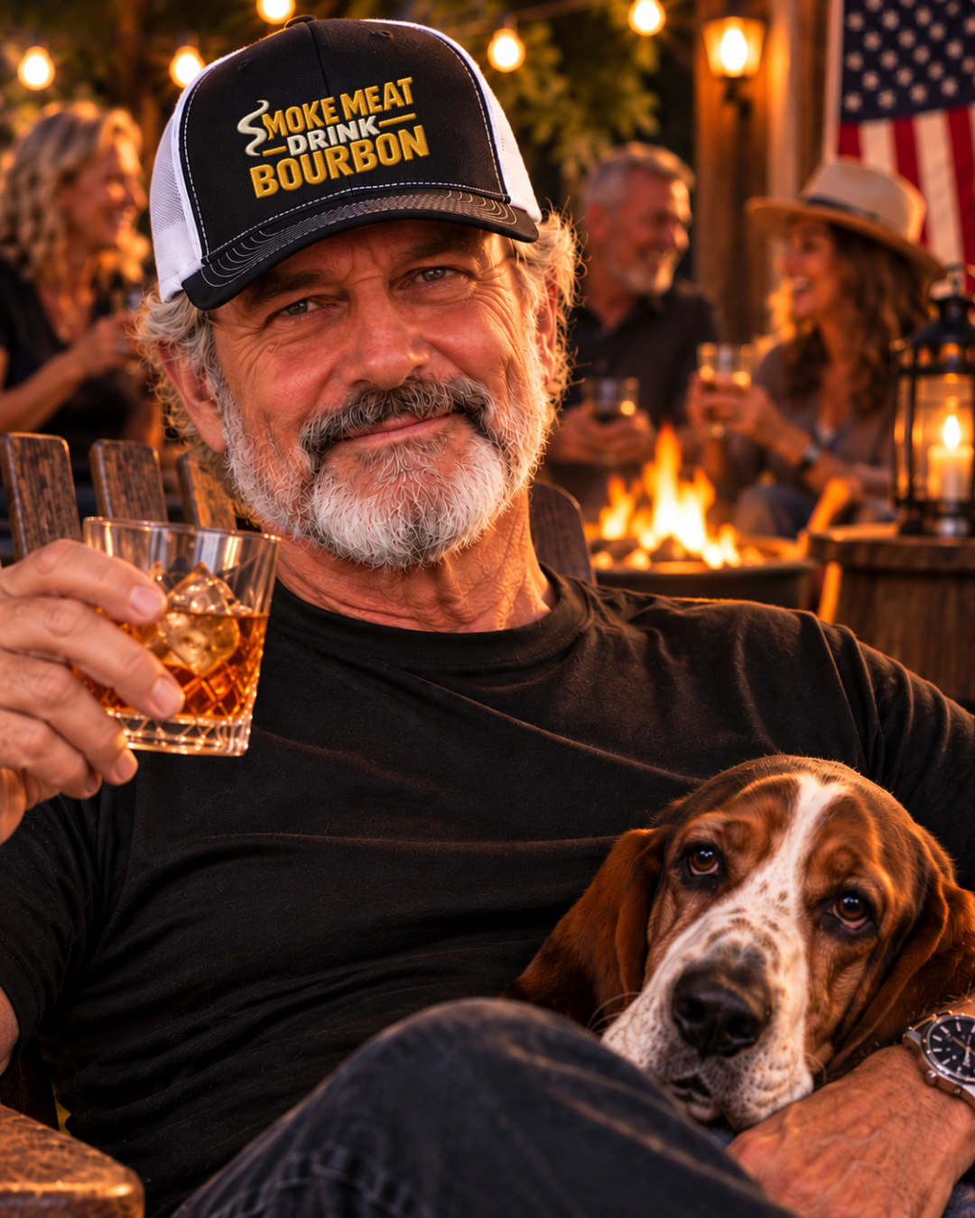 A man at a warm evening gathering wears a black and white trucker hat with the text 'SMOKE MEAT DRINK BOURBON' in yellow. He holds a glass of amber liquor while a brown and white dog rests on his lap.