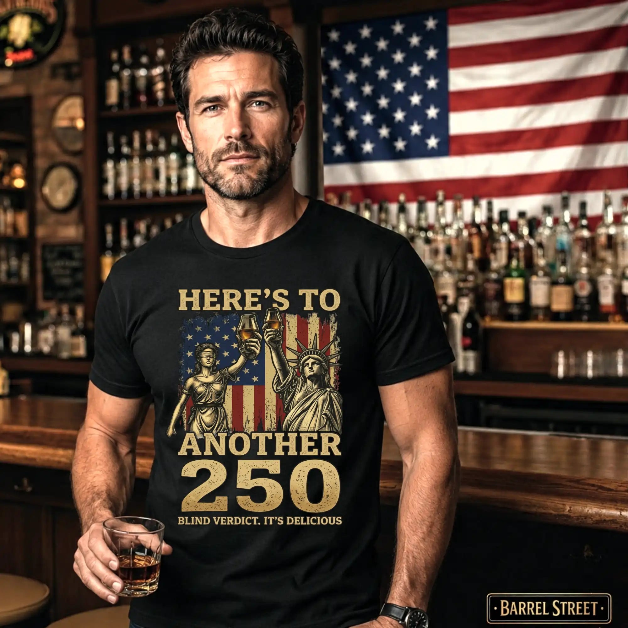 Man wearing a black t-shirt with a graphic design in a bar setting, holding a glass of whiskey.