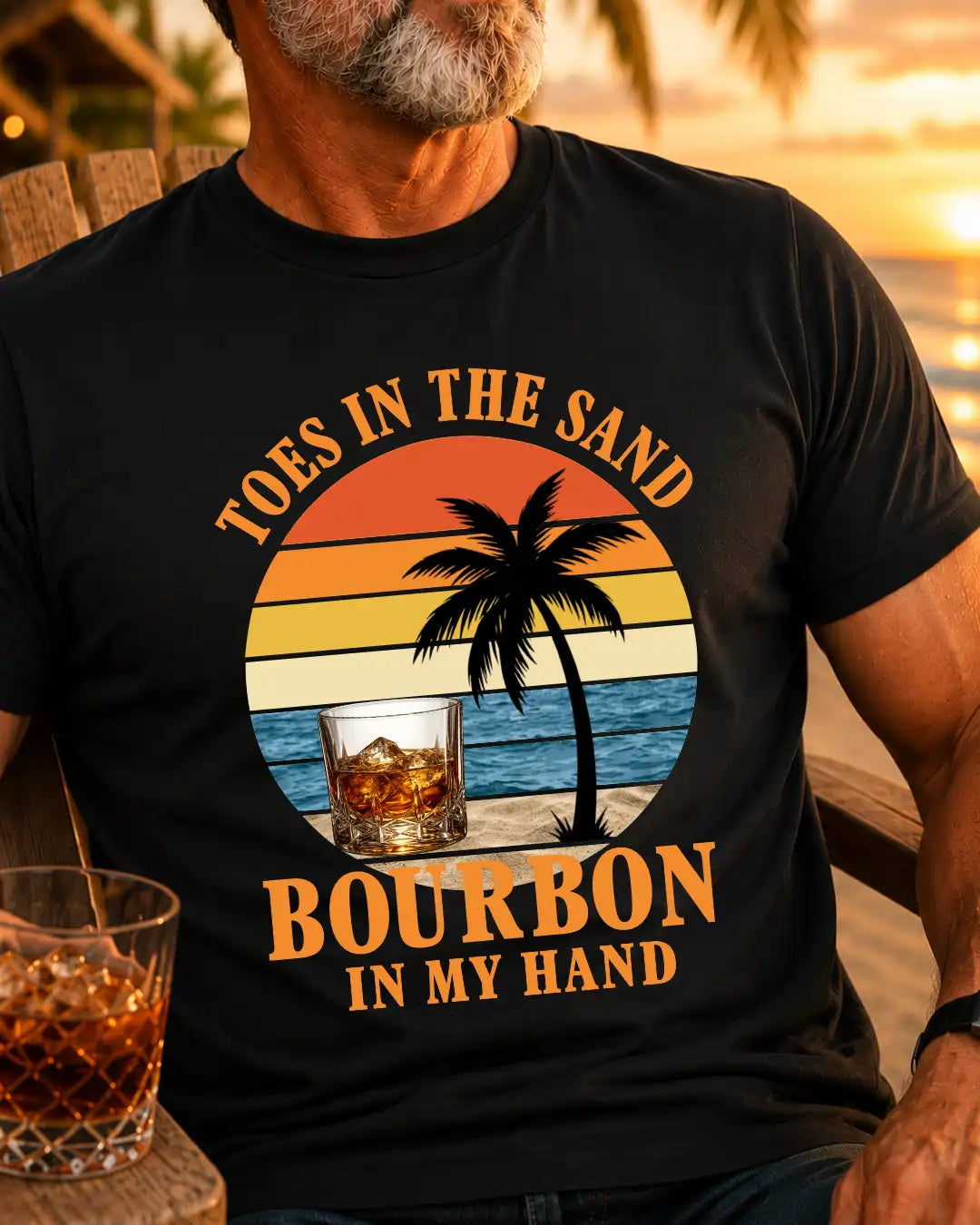 A man wearing a black graphic t-shirt with a retro sunset beach design and the text 'TOES IN THE SAND BOURBON IN MY HAND'.
