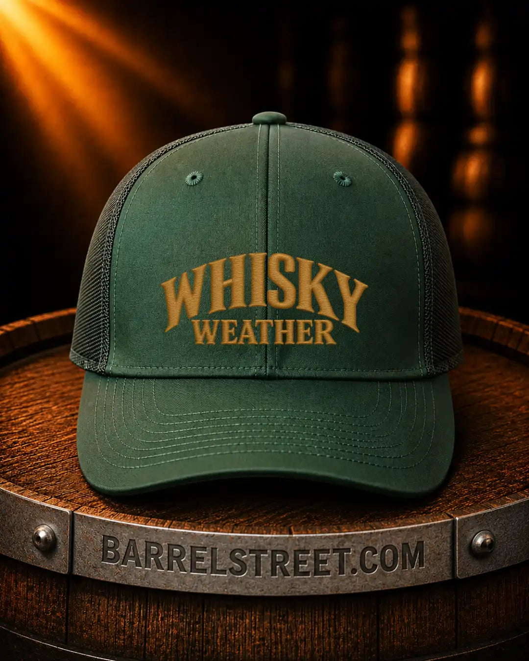 A dark green trucker-style cap with 'WHISKY WEATHER' embroidered in gold on the front, displayed on a wooden barrel with a warm, glowing background.